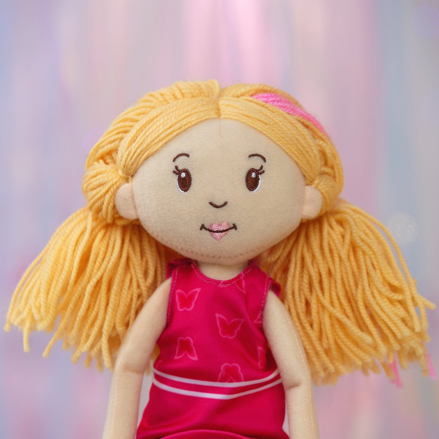 Plush doll with blonde hair and a pink dress against a blurred background